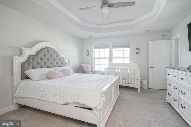 carpeted bedroom featuring ceiling fan and a raised ceiling