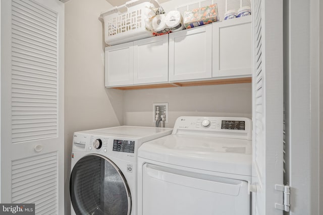 laundry area with separate washer and dryer and cabinets