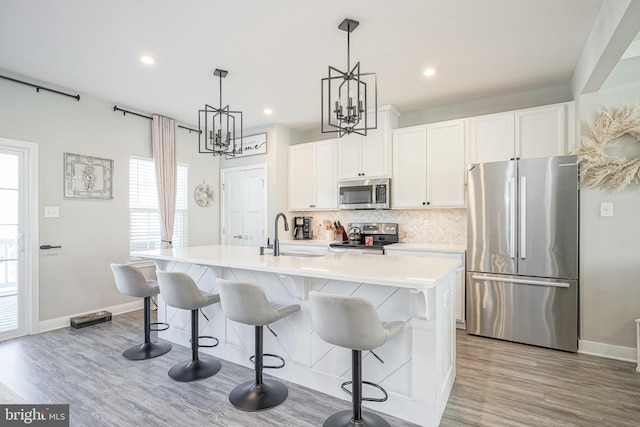 kitchen featuring sink, white cabinetry, stainless steel appliances, and a kitchen island with sink