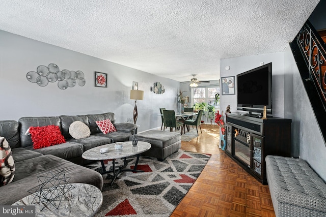 living room featuring a textured ceiling, ceiling fan, and parquet flooring