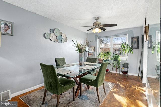 dining area featuring dark parquet flooring, a textured ceiling, and ceiling fan