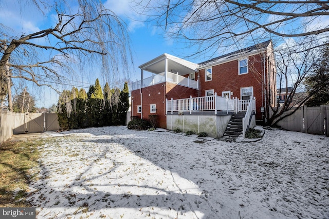 snow covered rear of property featuring a balcony