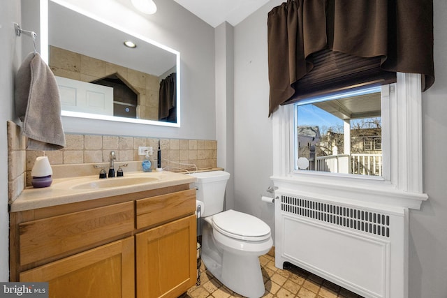 bathroom with radiator heating unit, vanity, tasteful backsplash, and toilet