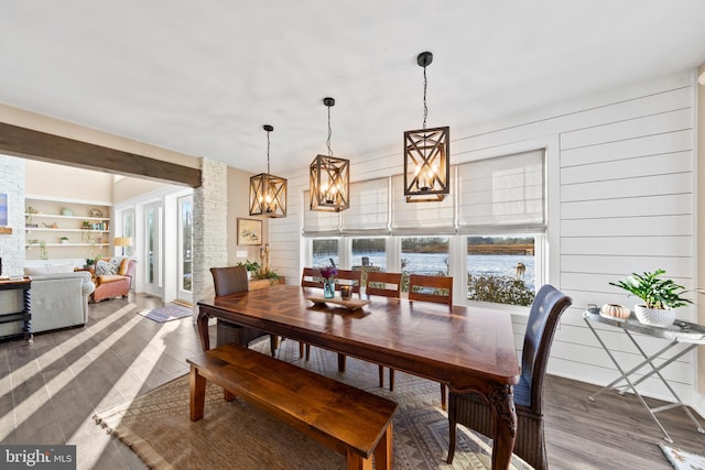 dining room featuring wood walls, built in features, a chandelier, and hardwood / wood-style floors