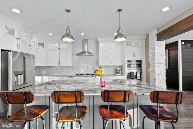 kitchen with stainless steel appliances, wall chimney range hood, and white cabinets