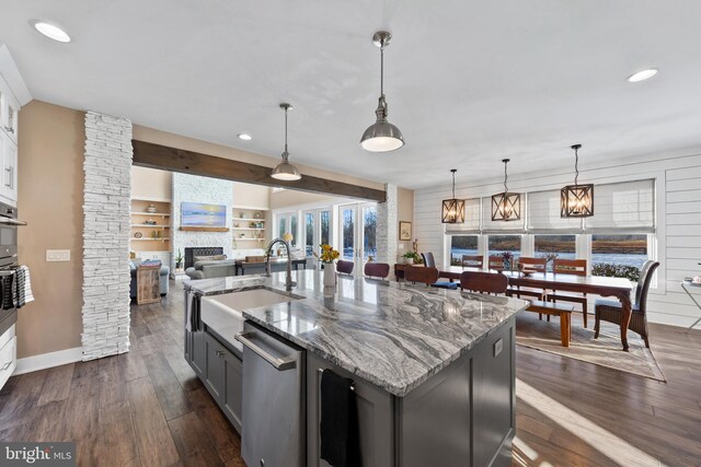 kitchen featuring sink, white cabinets, decorative light fixtures, built in features, and a center island with sink