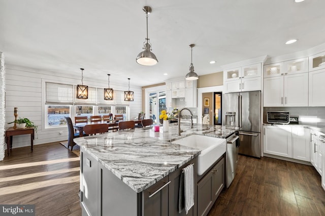 kitchen featuring stainless steel appliances, dark wood-type flooring, a spacious island, white cabinets, and sink