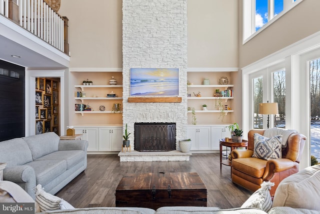 living room with a high ceiling, a fireplace, and built in features