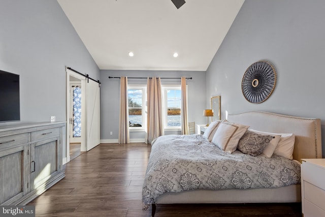 bedroom featuring vaulted ceiling, a barn door, and dark hardwood / wood-style floors