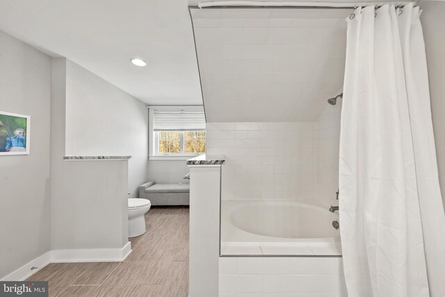 bathroom featuring shower / bathtub combination with curtain, hardwood / wood-style flooring, and toilet