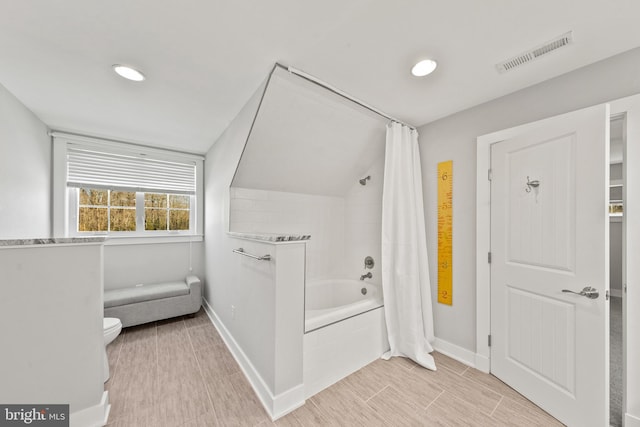 bathroom with lofted ceiling, toilet, and shower / bathtub combination with curtain