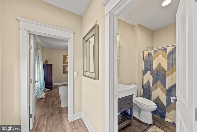 bathroom with toilet, wood-type flooring, and curtained shower