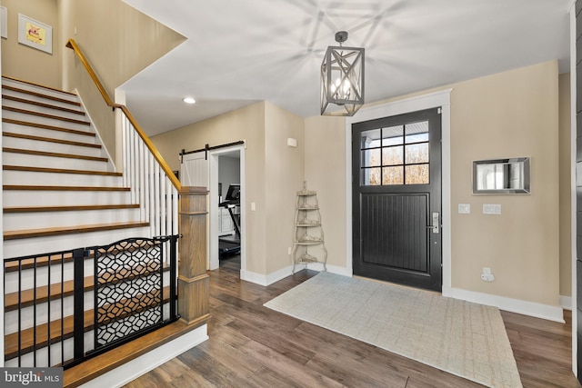 foyer with a chandelier, a barn door, and dark wood-type flooring