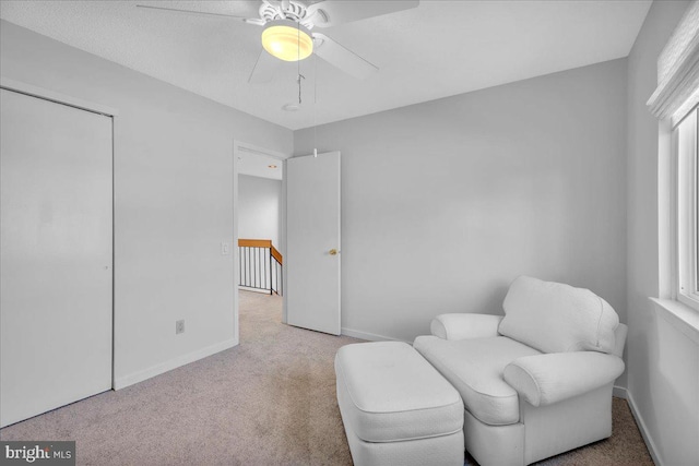 living area featuring a wealth of natural light, light colored carpet, and ceiling fan