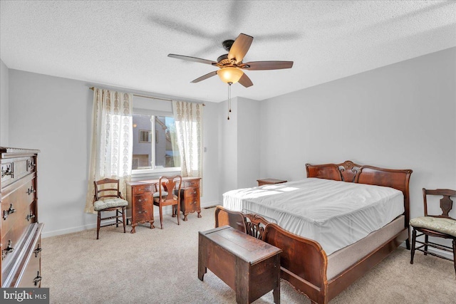 carpeted bedroom featuring ceiling fan and a textured ceiling