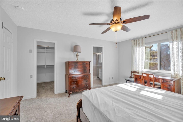 carpeted bedroom featuring a textured ceiling, ceiling fan, a spacious closet, connected bathroom, and a closet