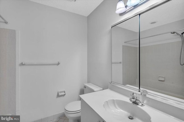 bathroom with tile patterned floors, vanity, a textured ceiling, a shower, and toilet