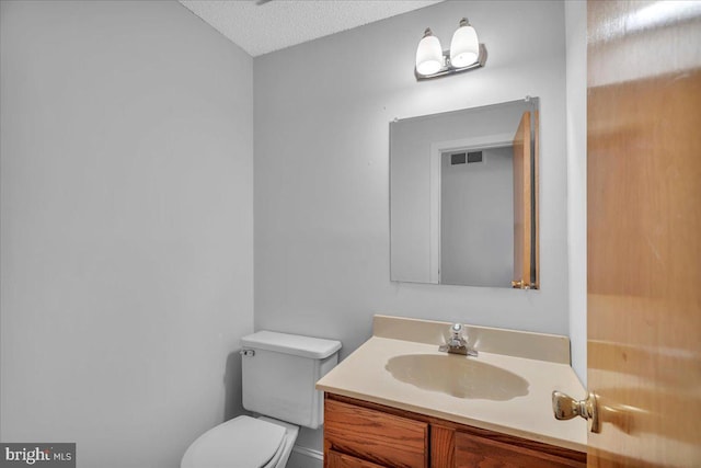 bathroom with a textured ceiling, vanity, and toilet