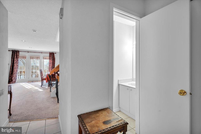 corridor with light colored carpet and a textured ceiling