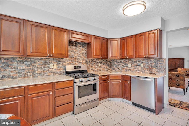 kitchen with light tile patterned floors, a textured ceiling, stainless steel appliances, and tasteful backsplash