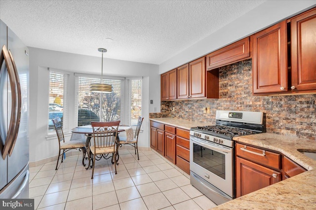 kitchen featuring light stone countertops, pendant lighting, a textured ceiling, light tile patterned floors, and appliances with stainless steel finishes