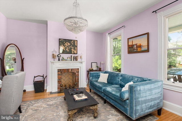 living room featuring a fireplace, wood-type flooring, and an inviting chandelier