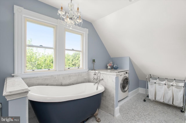 bathroom featuring washer / clothes dryer, a washtub, lofted ceiling, and an inviting chandelier