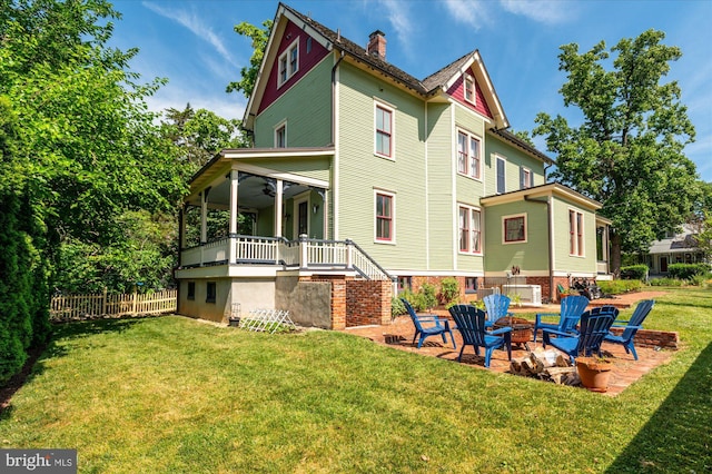 back of house featuring a porch, a fire pit, ceiling fan, and a lawn