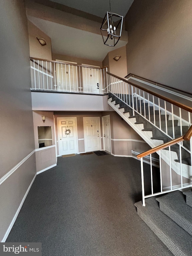 stairway with carpet flooring, a chandelier, and high vaulted ceiling