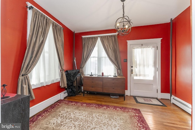 foyer entrance featuring baseboard heating, a chandelier, and hardwood / wood-style flooring