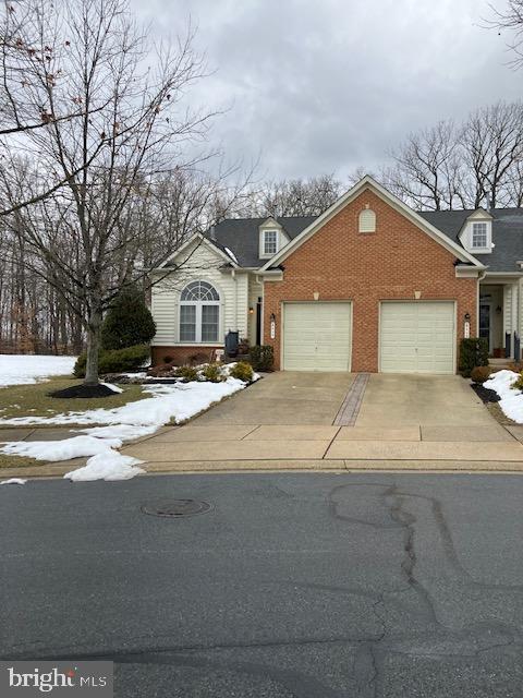 traditional home with a garage, brick siding, and concrete driveway