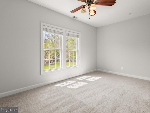 carpeted spare room featuring ceiling fan, baseboards, and visible vents
