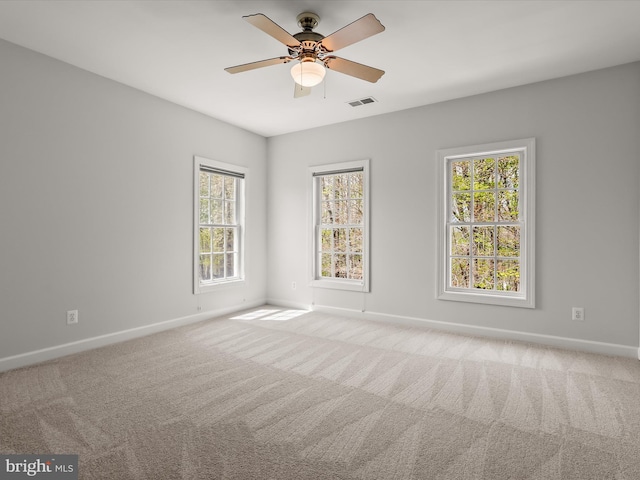 carpeted spare room featuring ceiling fan, baseboards, and visible vents