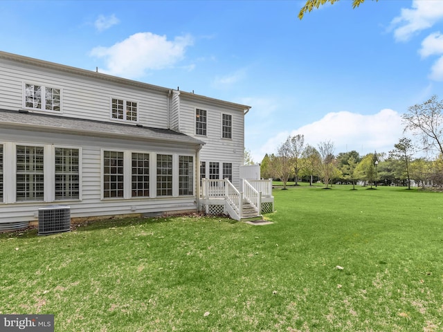 rear view of house featuring central AC, a wooden deck, and a lawn