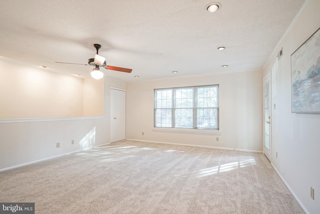 carpeted empty room featuring a textured ceiling, ceiling fan, and crown molding