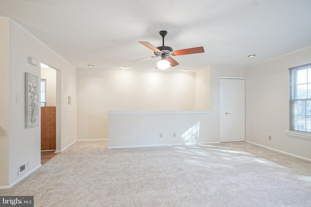 carpeted spare room with ceiling fan and crown molding