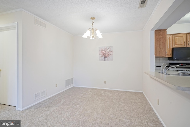 unfurnished dining area with a textured ceiling, an inviting chandelier, light colored carpet, ornamental molding, and sink