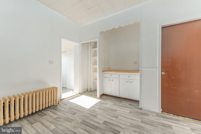 empty room with crown molding, radiator, and light hardwood / wood-style flooring