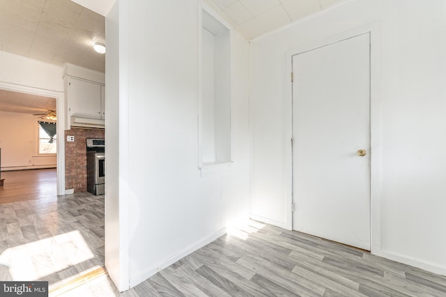 hallway featuring a baseboard heating unit and light hardwood / wood-style floors