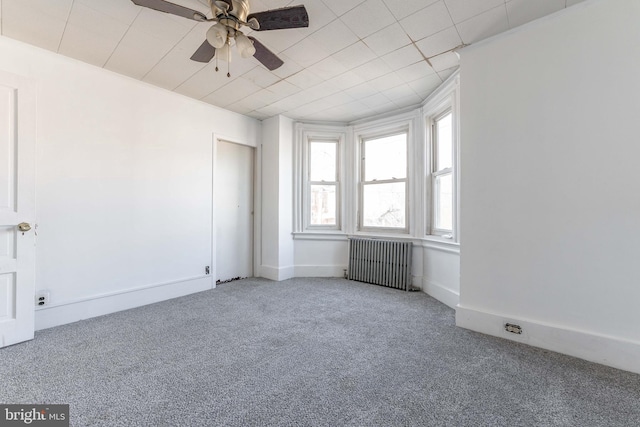 spare room featuring ceiling fan, radiator heating unit, and carpet