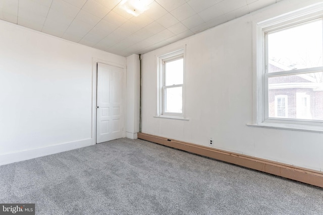 spare room featuring a baseboard heating unit and carpet floors