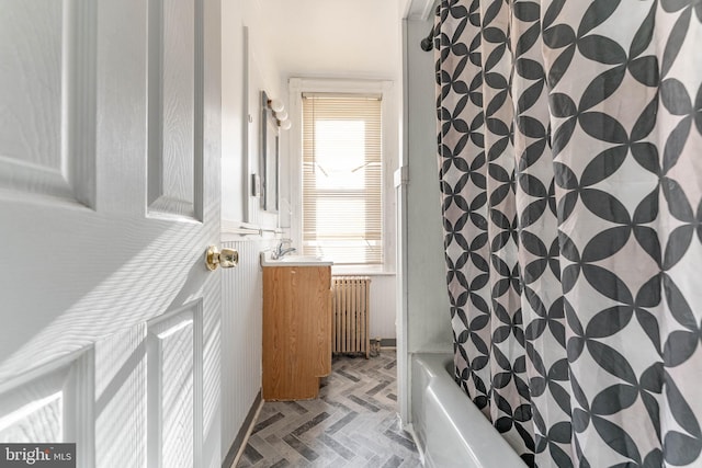 bathroom with shower / tub combo, radiator heating unit, and vanity