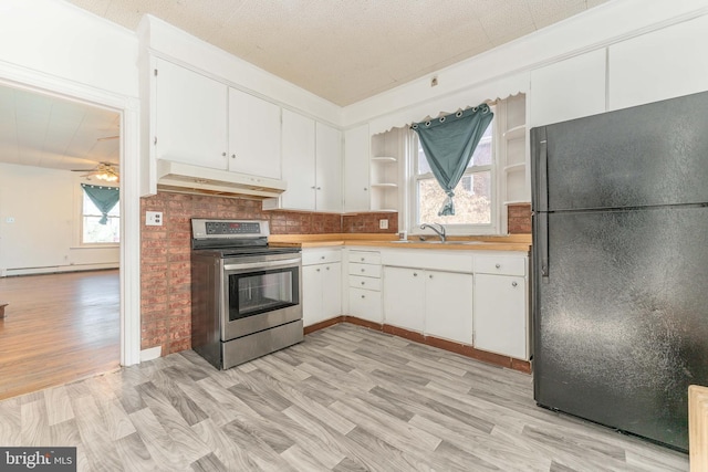 kitchen featuring black refrigerator, ceiling fan, stainless steel range with electric stovetop, sink, and white cabinetry