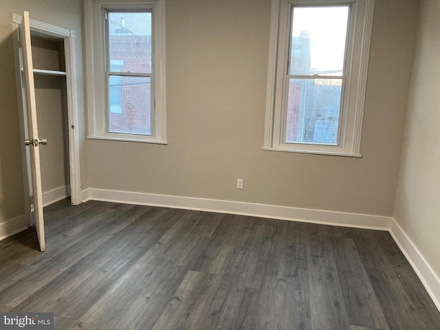 unfurnished bedroom with dark wood-type flooring and multiple windows