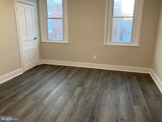 spare room featuring dark wood-type flooring and a healthy amount of sunlight