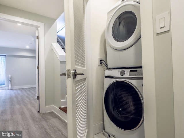 clothes washing area featuring stacked washer and dryer and light hardwood / wood-style flooring