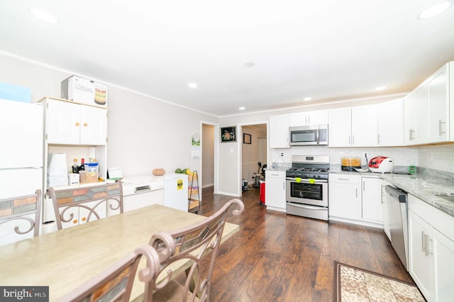 kitchen with white cabinets, stainless steel appliances, light stone countertops, and dark wood-type flooring