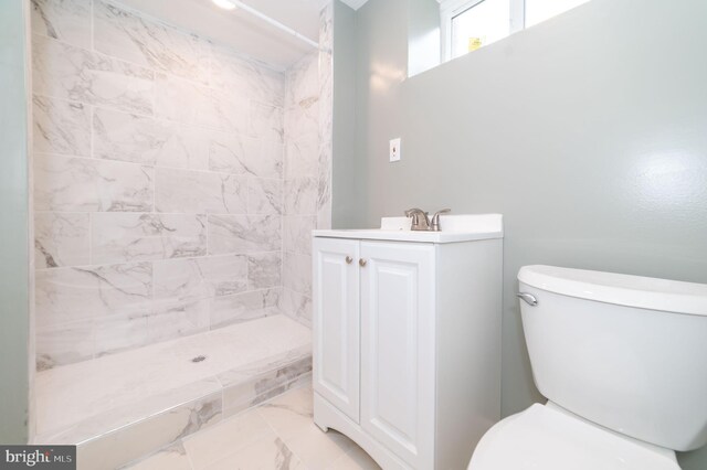 bathroom with a tile shower, vanity, and toilet