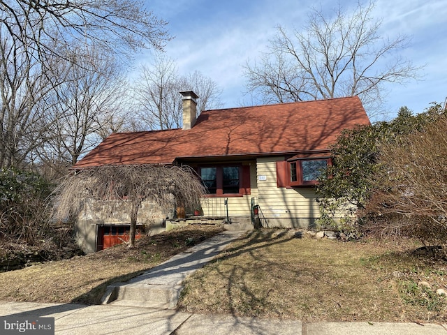 view of side of property featuring a chimney and a shingled roof