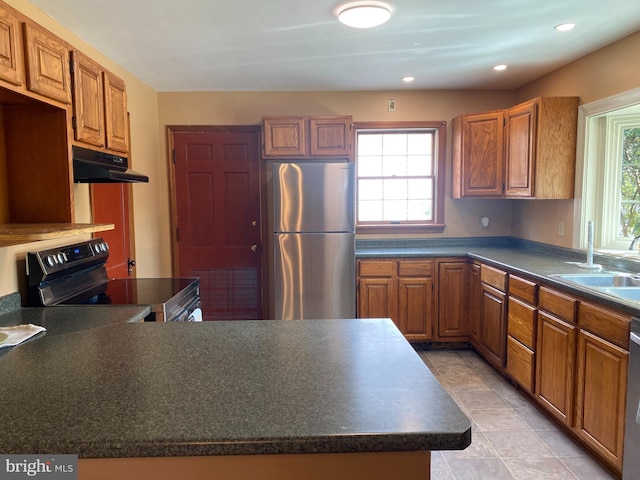 kitchen featuring under cabinet range hood, stainless steel appliances, dark countertops, and a sink